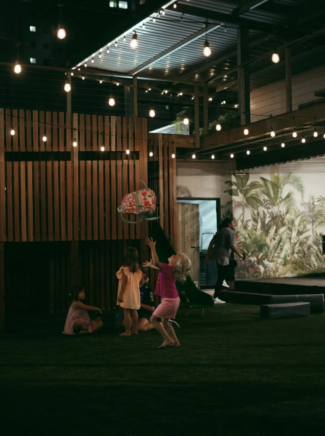 Kids playing at night under string lights