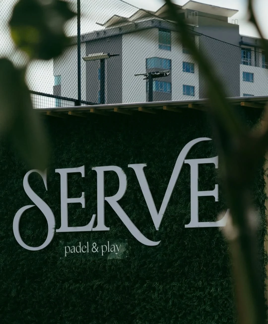 SERVE padel sign on green hedge